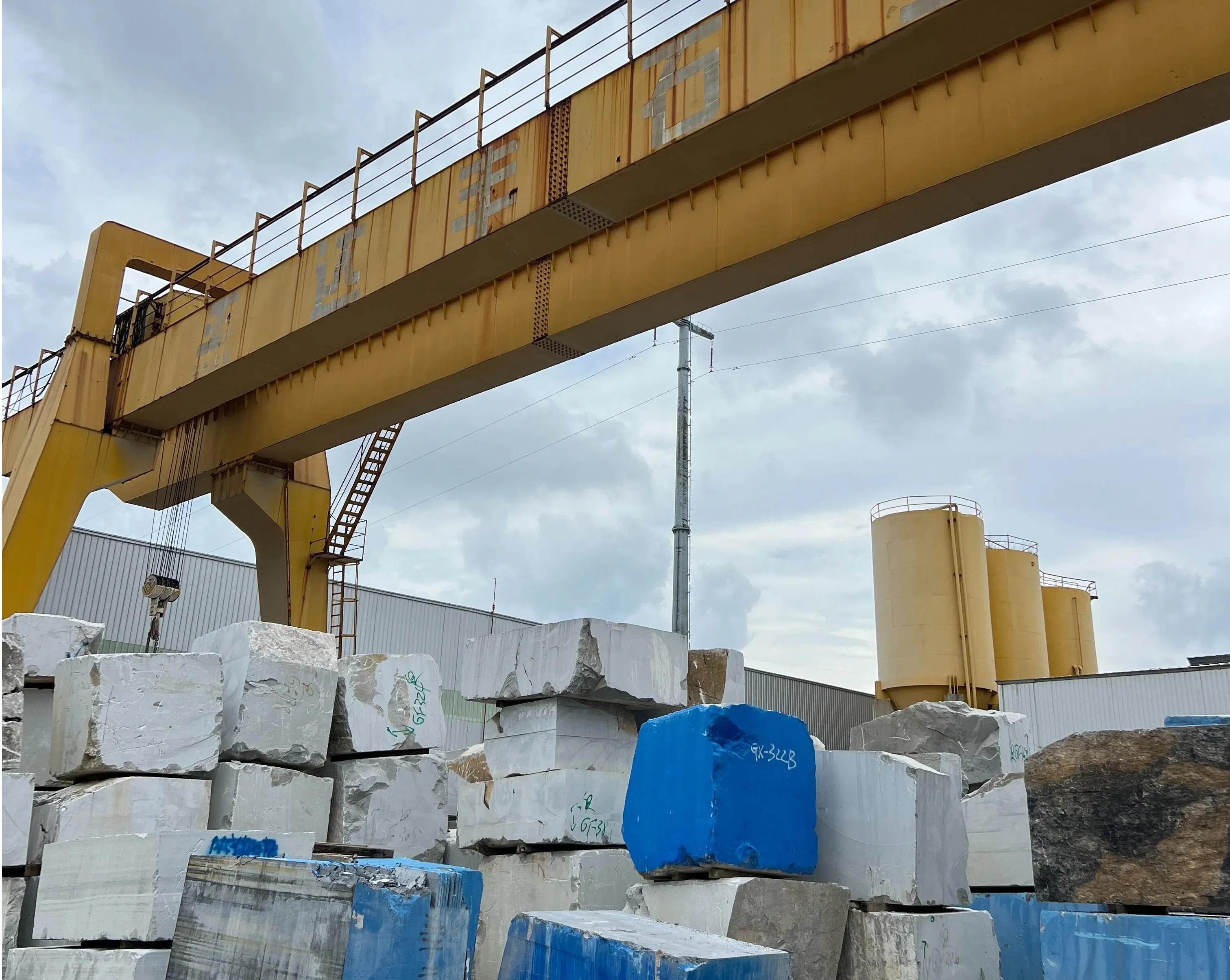 Stone slabs racked in a production hall, moved by overhead crane